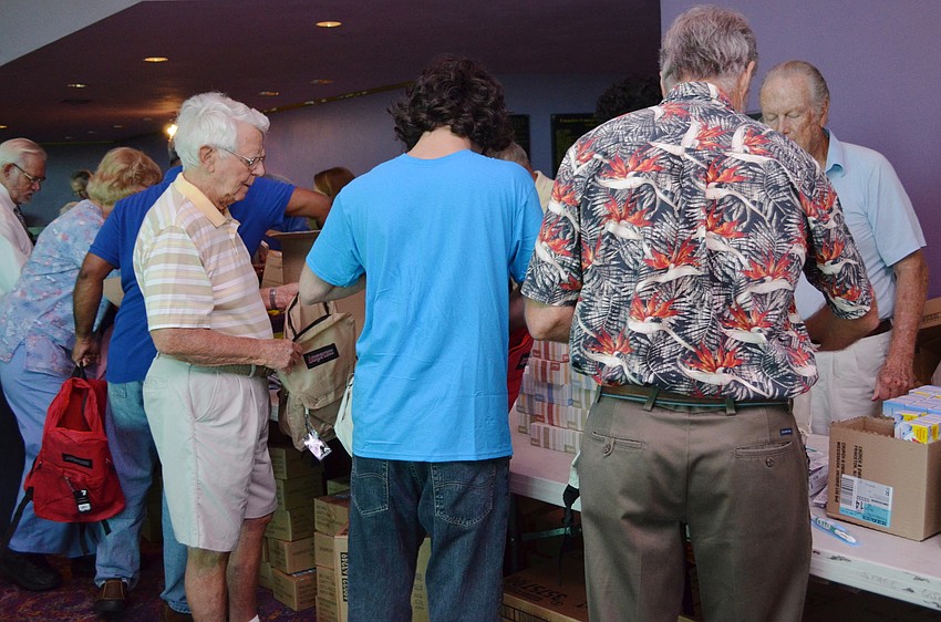 Volunteers fill the backpacks with school supplies.