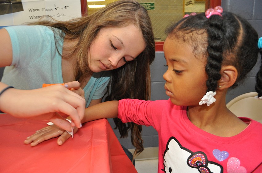 Haile Middle Schoolâ€™s Olivia Perez puts a heart tattoo upon Kaelyn Poole, 3.