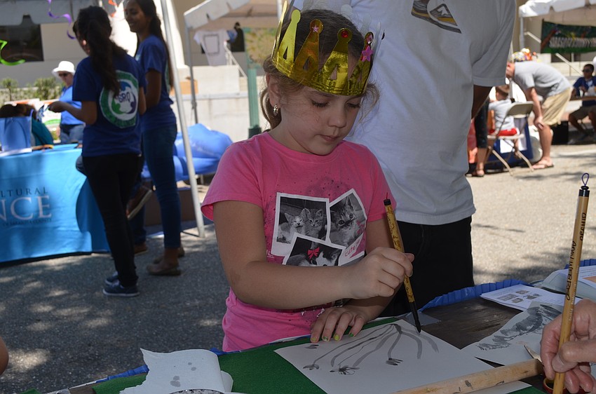 Kylei Rydzinkski learns oriental brush painting at the Association of Florida Teaching Artists booth.
