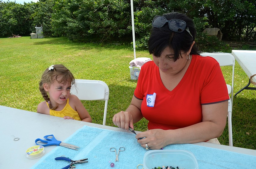 Five-year-old Avah Meadows watches Bonnie McKee make a bracelet.