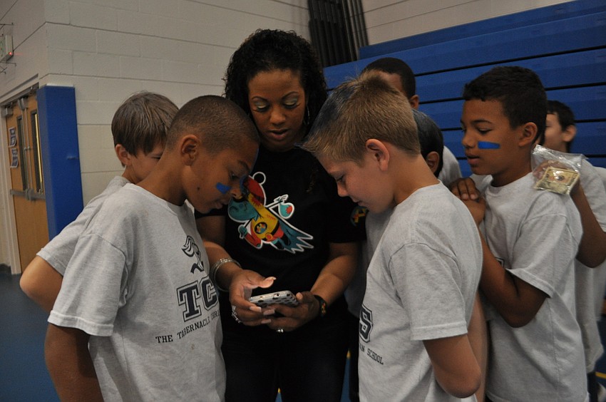 Jaden Valdez, left, and Jacob Stilwell, right, look over pictures on the phone ofTabernacle parent Alex Hallett, center.