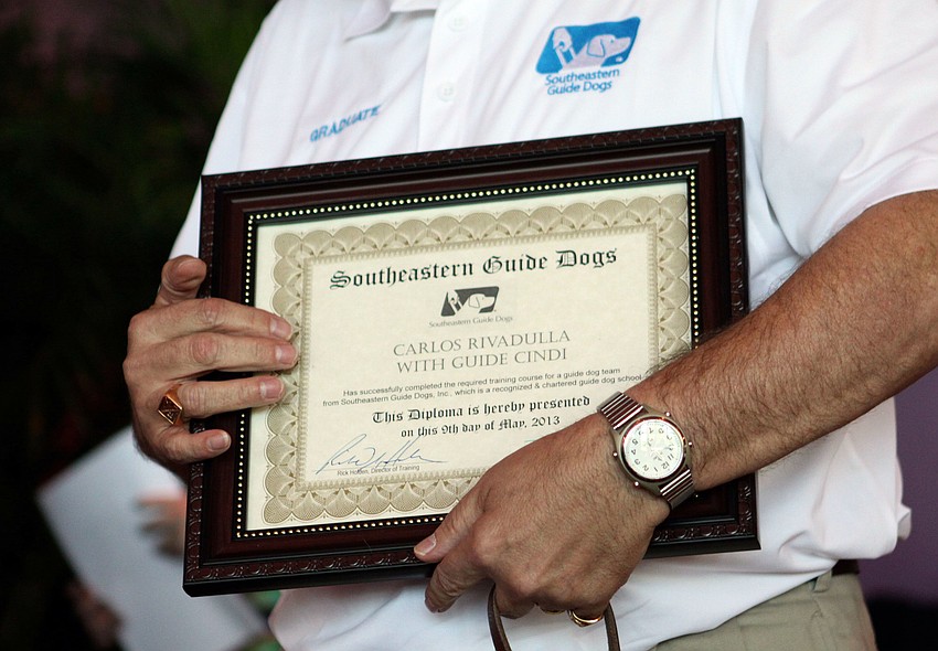 Carlos Rivadulla holds the diploma that he and his guide dog Cindi received at graduation.
