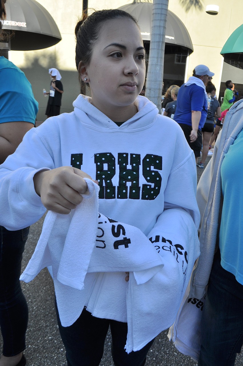 Lakewood Ranch High School student Morgan Mirandilla hands out towels as runners finish the race.