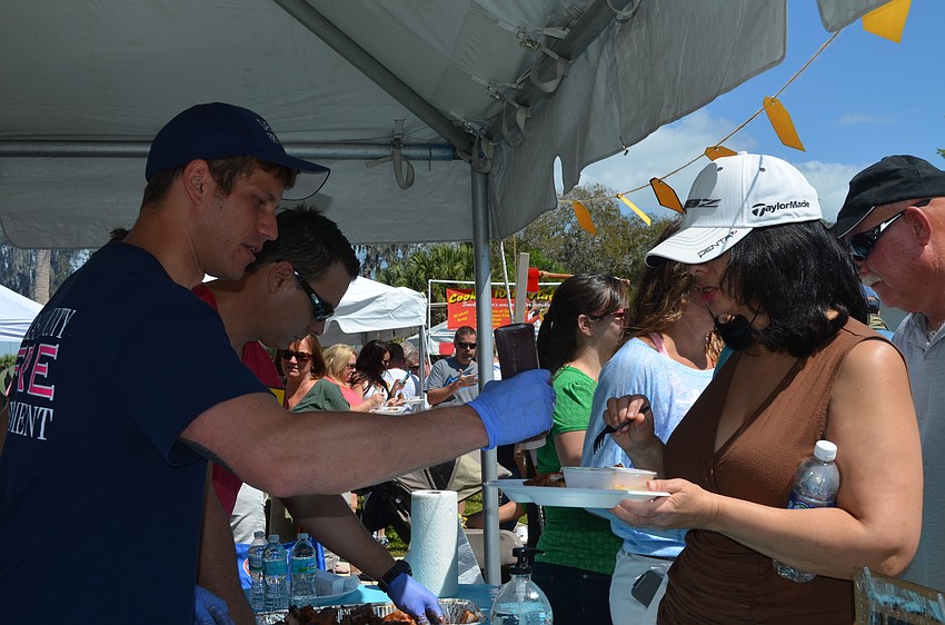 Volunteer firefighter, Taylor Smith, helps Helaine Yedkoin to sauce.