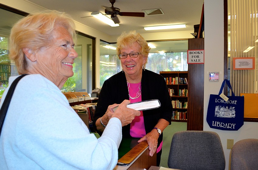 Charlotte Jensen buys a book from Hazel Steskal at the election week book sale at the Longboat Library.
