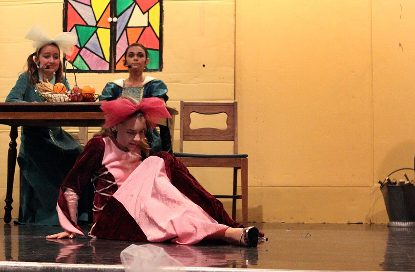 Portia, Carrie Dutting, falls out of her chair trying to put on the glass slipper.