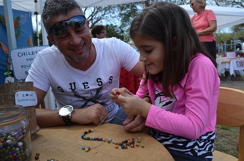 Oscar and Eva Revelli make a necklace.