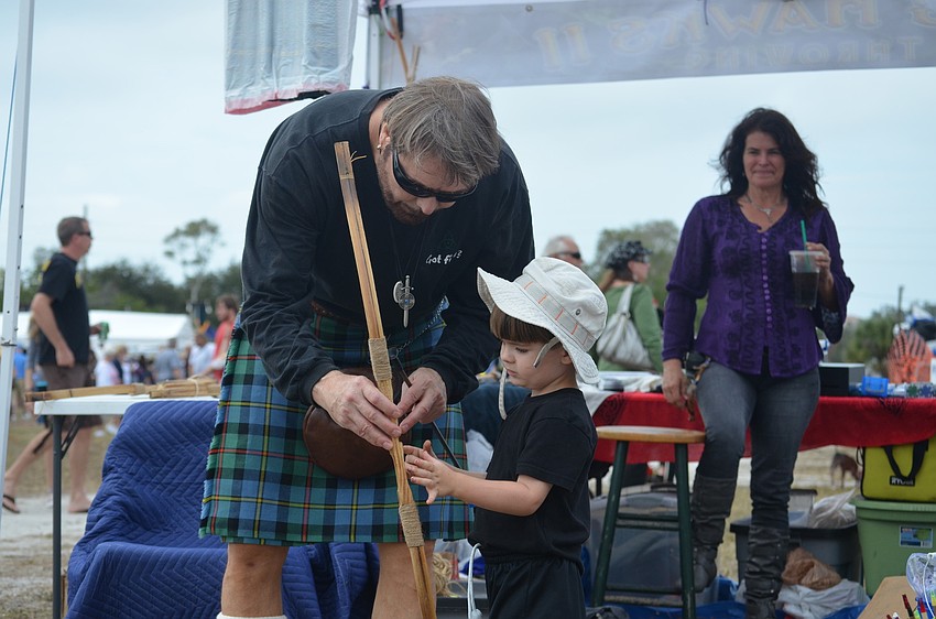 Stephen Stadler helps son, Wolfy, shoot a bow and arrow.