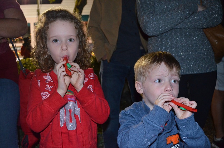 Brynn and Grant Raymond play kazoos they got from the parade.