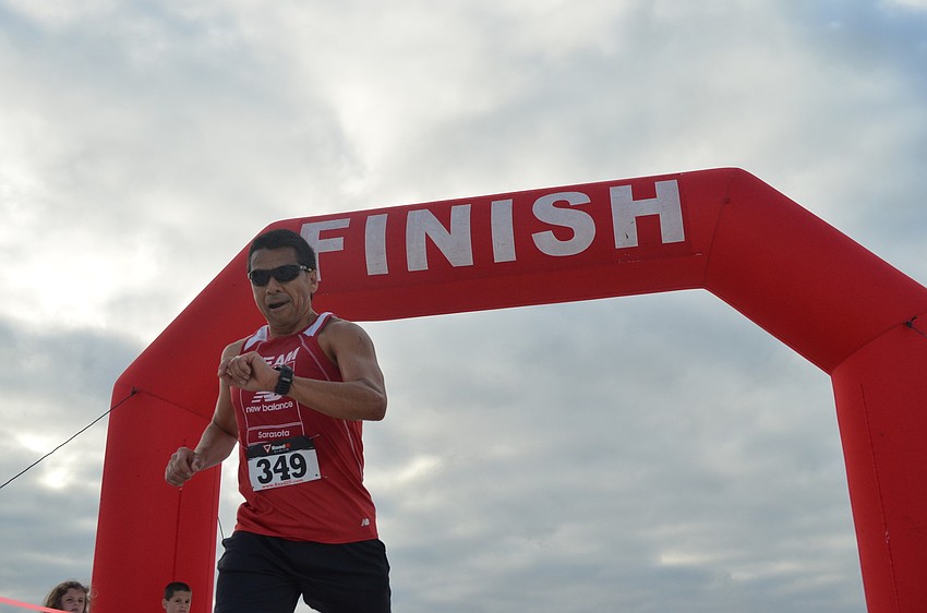 Ricardo Lomas checks his time as he crosses the finish line.