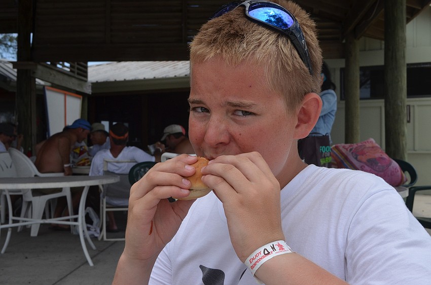 Anderson Brunsvold has been sailing for one year. He bites into a burger at the BBQ after the race at the Sarasota Sailing Squadron.