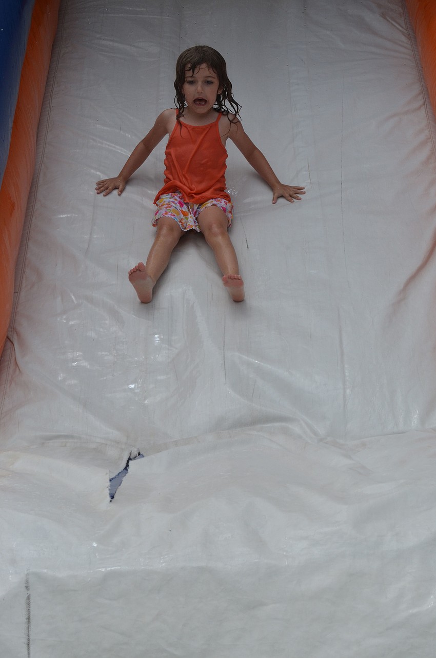 Marena Pagington slides down a slippery slide into a pool of water at the BBQ after the race.