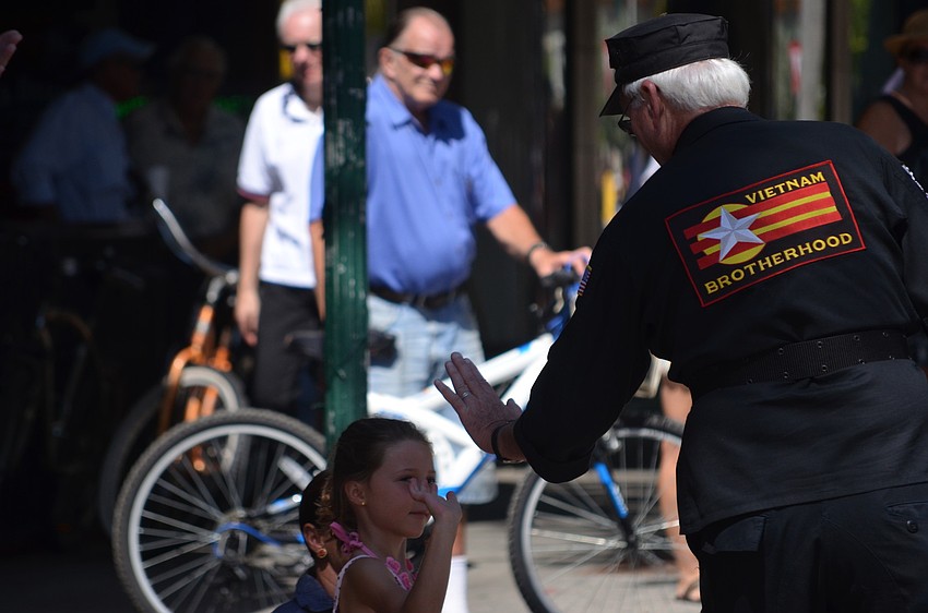 President of the Sarasota County Veterans Commission Andy Hooker gives children high fives as he passes them in the parade.