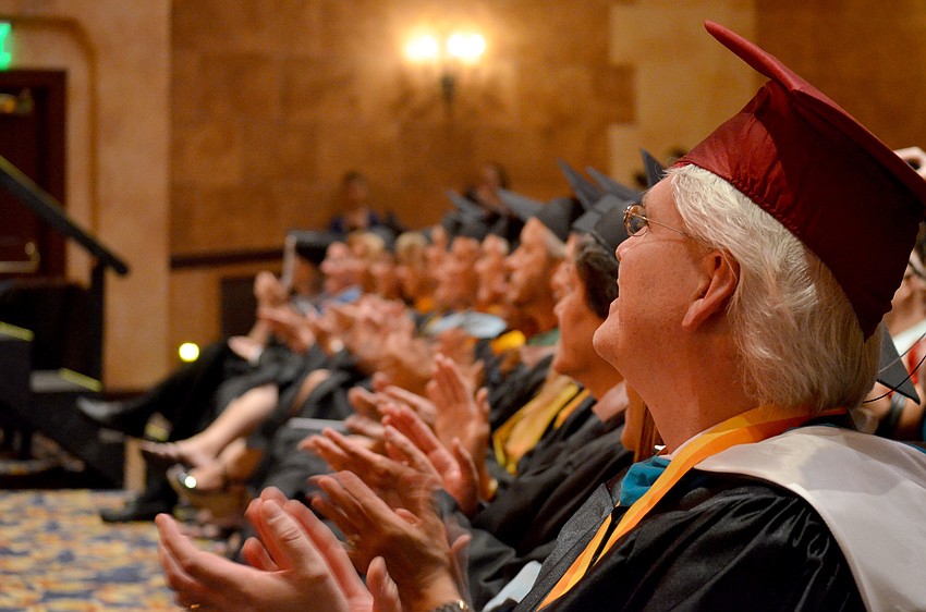 Faculty members applaud as seniors receive their diplomas.