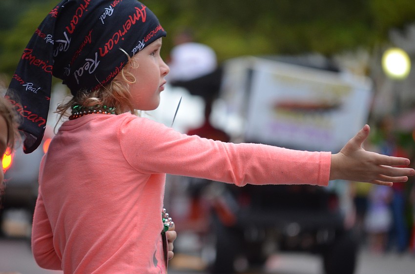 Jaidyn McAlister, 5, holds her hand out for more beads.
