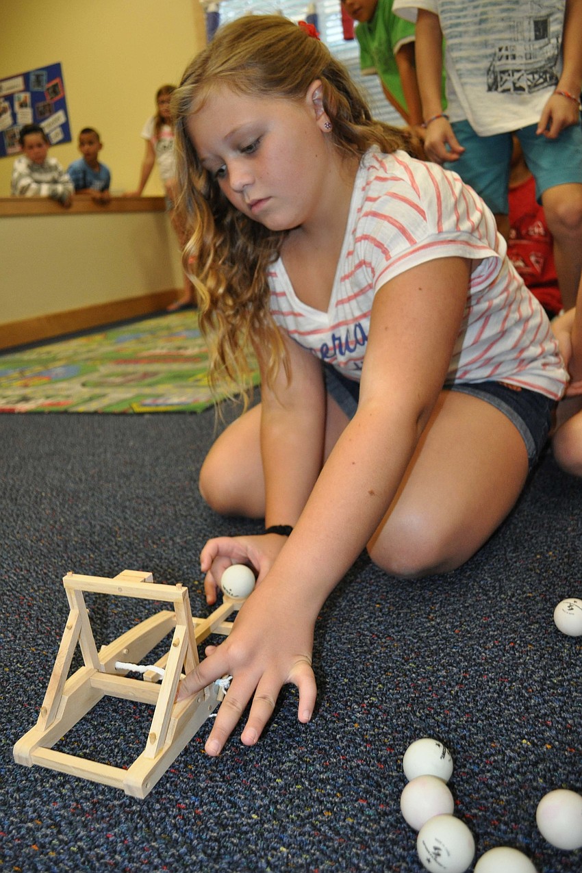 Samantha Torino, 11, tries to launch a ball so it lands in an inflatable pool about five feet away.