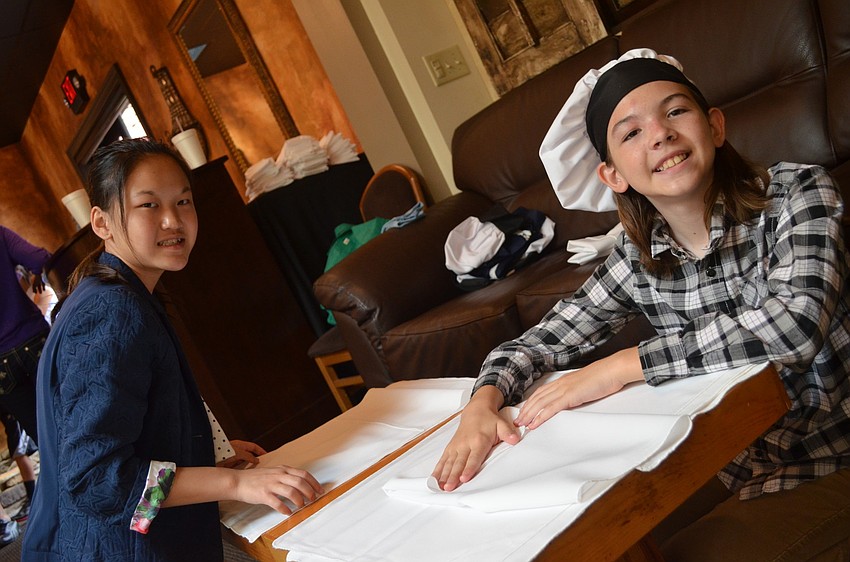 Maura Kent, 13, and Jack Filipanits, 11, fold napkins for guests before they arrive.