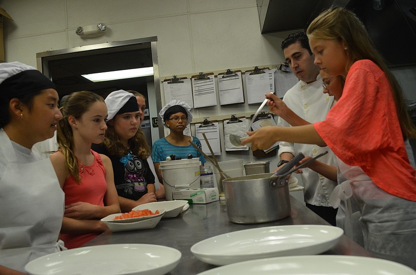Campers watch Samantha Reisky, 11, scoop piccata sauce for the artichokes into a bowl.