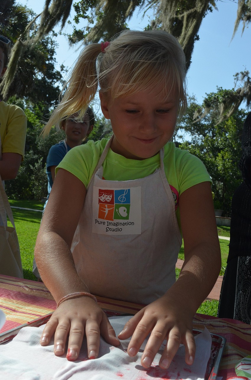Calynn Stewart, 7, prints leaves onto a canvas bag.
