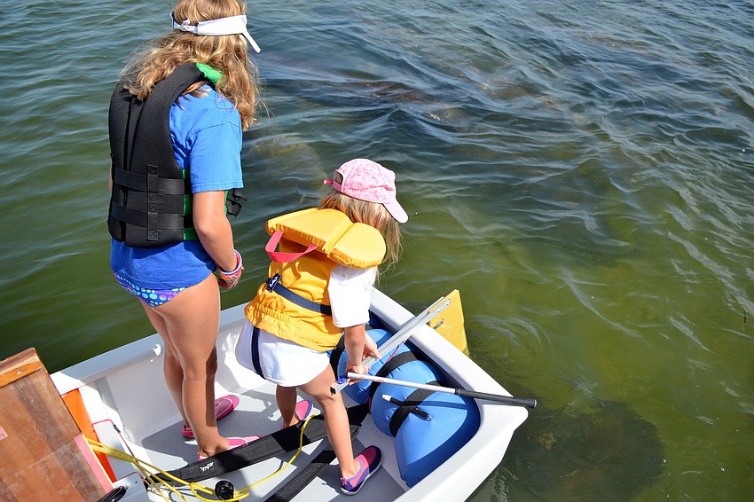 Katie and Shelby Fulton watch the herd of manatees swim past their boat.