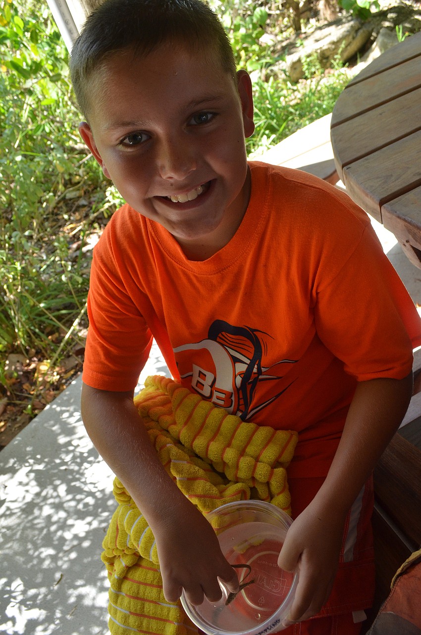 Adam Stump, 10, examines the spotted sea trout he caught in a trolling net with his partner 11-year-old Eric Hvideberg.