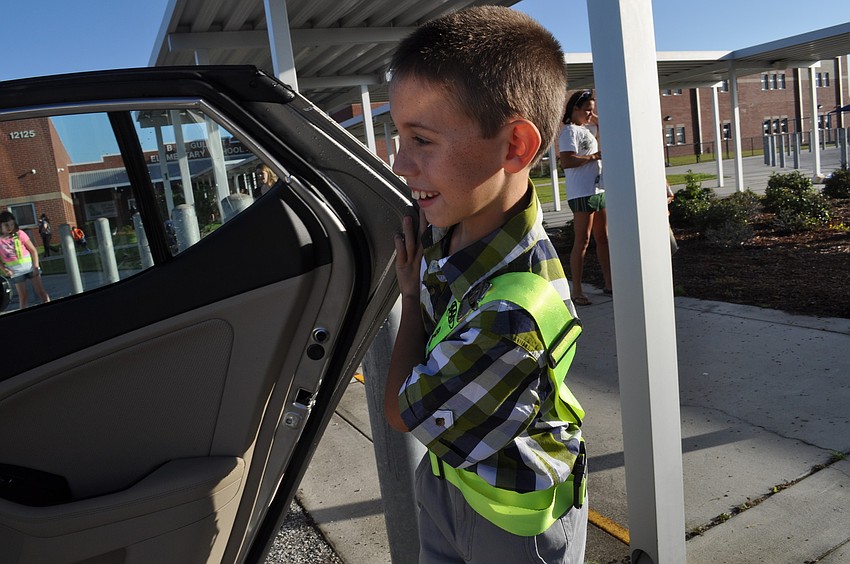 Gullett Elementary School fifth grader Dalton Roszel, a safety-patrol member, ushers children from their cars on the first day of school.