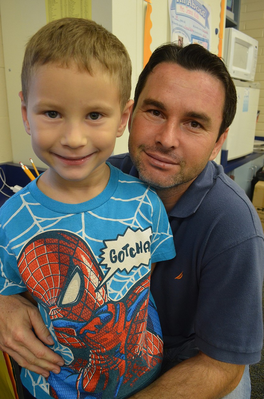 Pater Kalo plays on the computer with his son, Nathan, Tuesday morning.