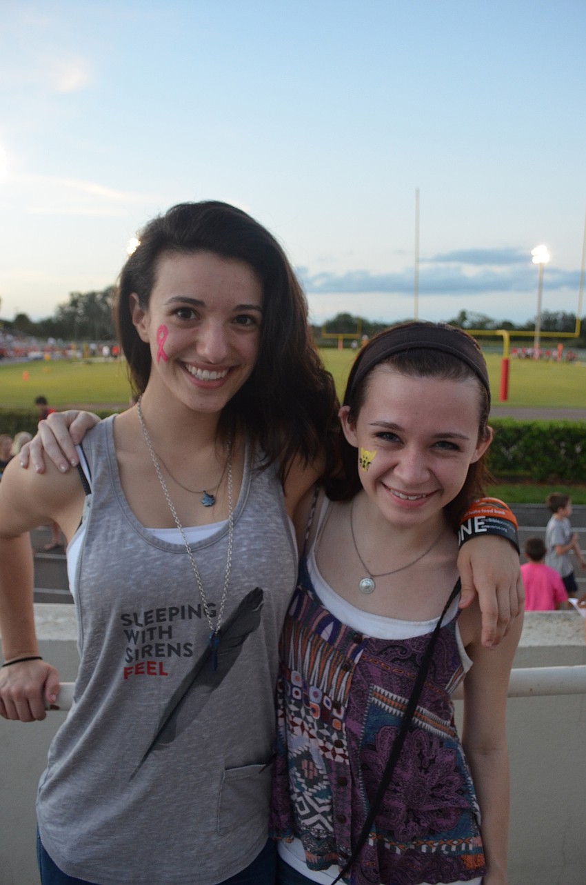 Alison Palmer, 16, and Lauren Seitz, 17, work the face painting table at the football game.