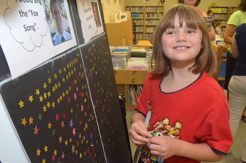 Morgan Walburn, 9, votes for a teacher to do something silly with a star sticker. Children voted to have a teacher dye her hair pink or another teacher to sing the â€œFox song.â€