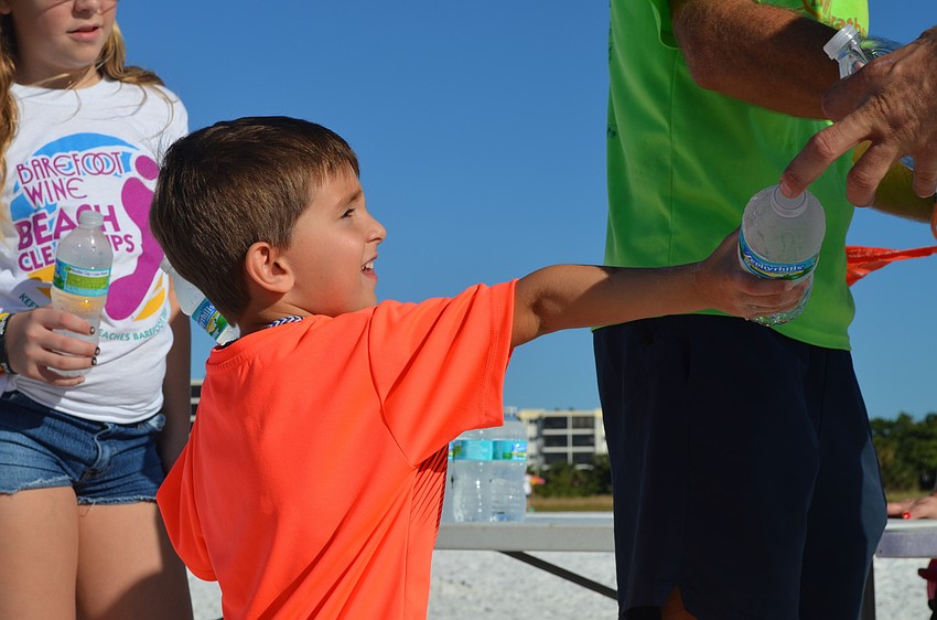Owen Adams hands water to the runners at the finish line