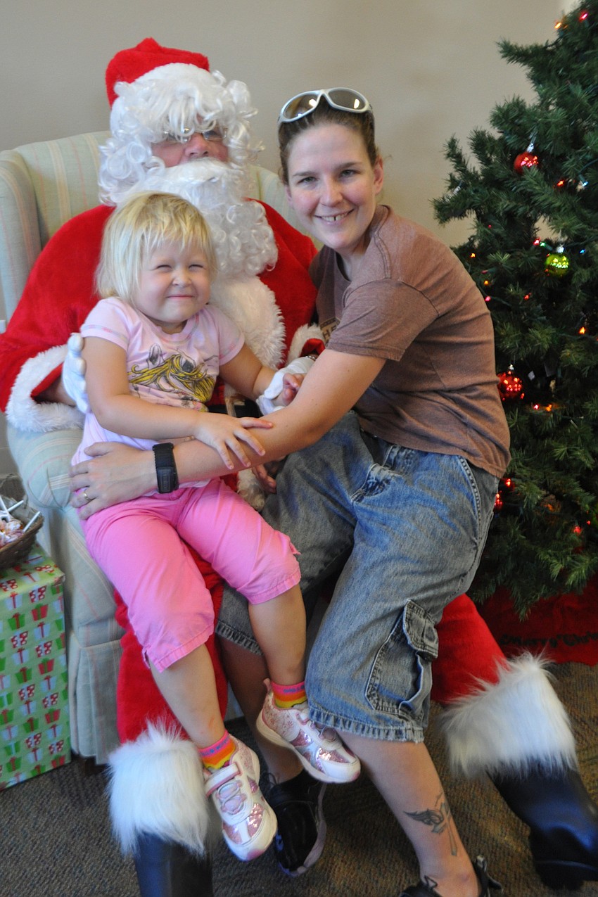 Zofia Milligan, 3, grabs a picture with Santa with her mom, Heather.