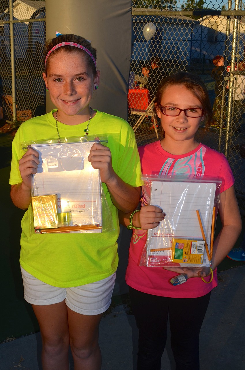 Ten-year-olds Elaina Karow and Bella Dombroski show off their new school supplies.