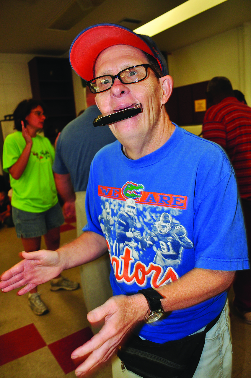 David Kalsz plays the harmonica during Bobby Mitchell's July 19 performance at Community Haven for Adults and Children with Disabilities.