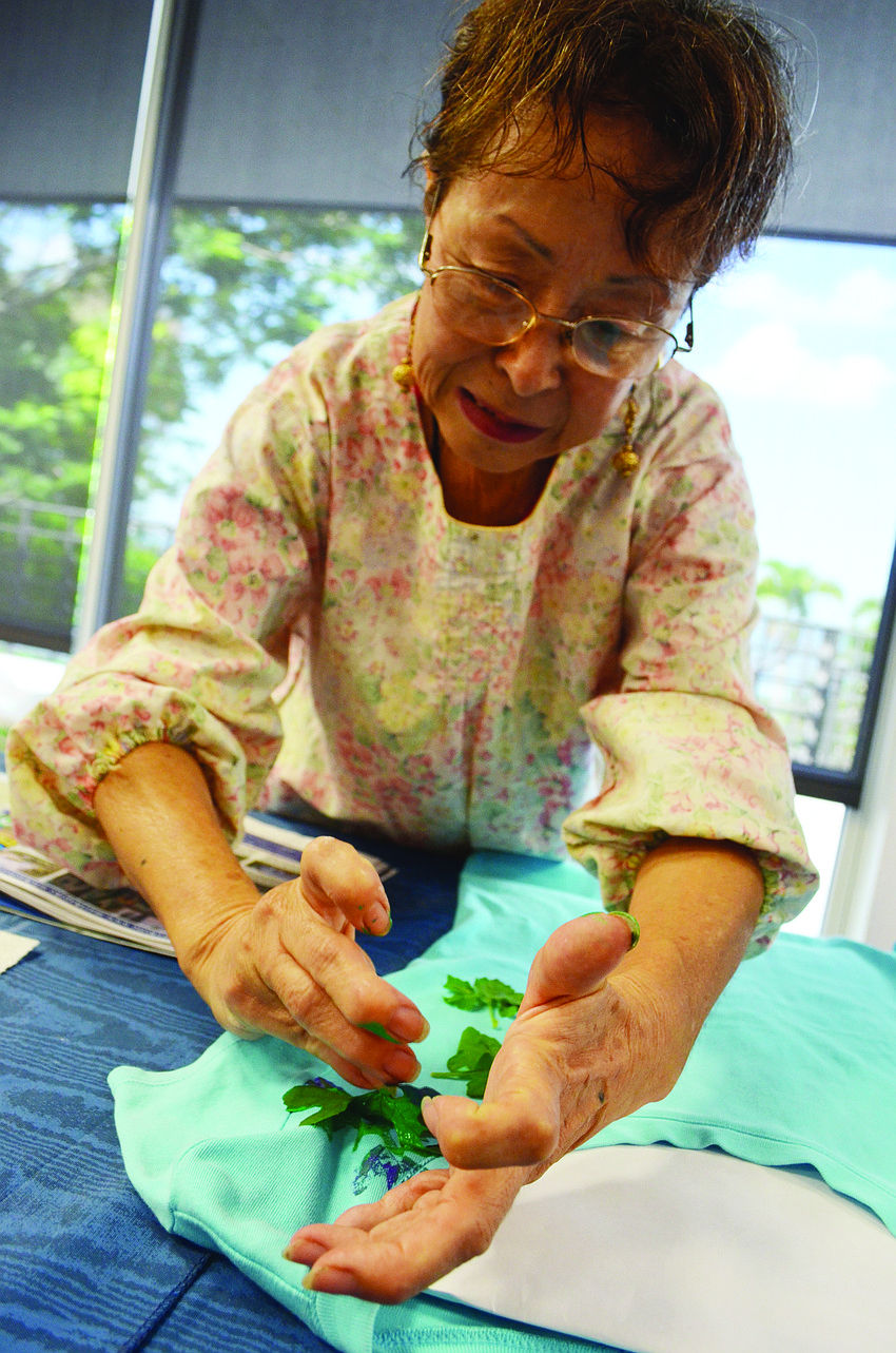Aiko Anderson demonstrates calligraphy painting on T-shirts during an Ikebana Sarasota Chapter No. 115 meeting.