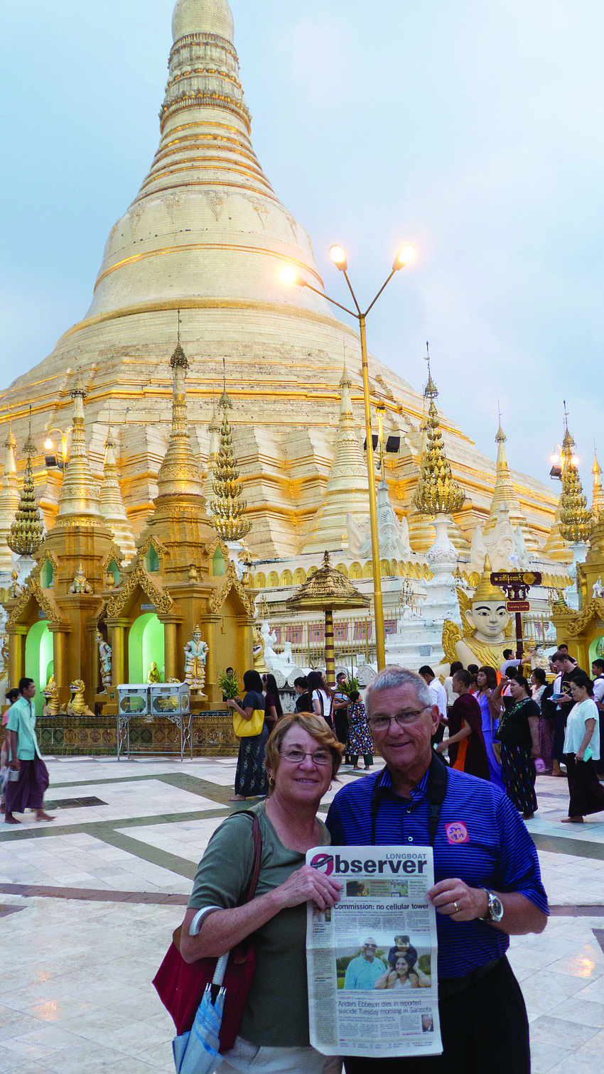 GOOD AS GOLD. Barb and Ron Archbold catch up on their Longboat Observer news at the Shwedagon Pagoda in Yangon, Myanmar.