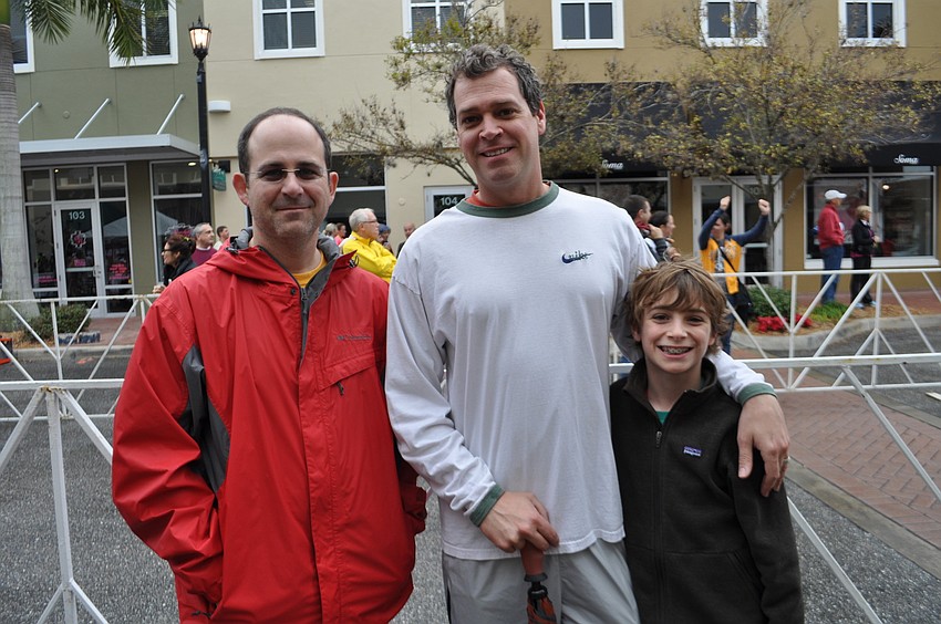 Jody Abrams and Shep Frenchman, with his son, Sebastian, watch their wives cross the finish line.