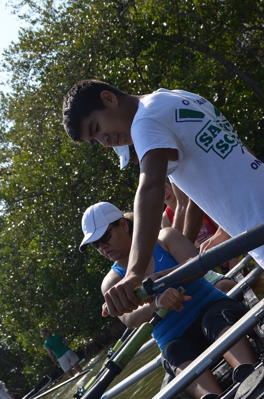 Dante Zuniga teaches his mom Veronica how to position her hands on the oars.