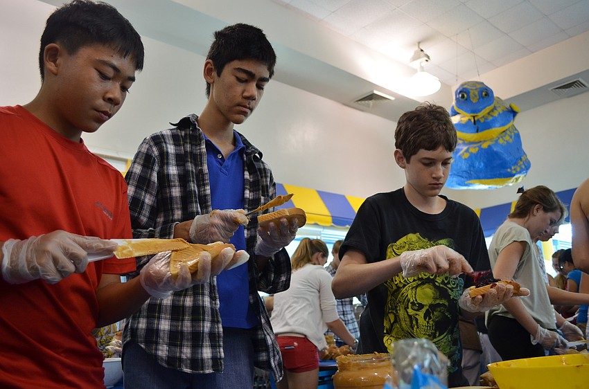 Eight graders Phillip Tran, Max Borukhov and Max Chambers spread soy butter on bread.