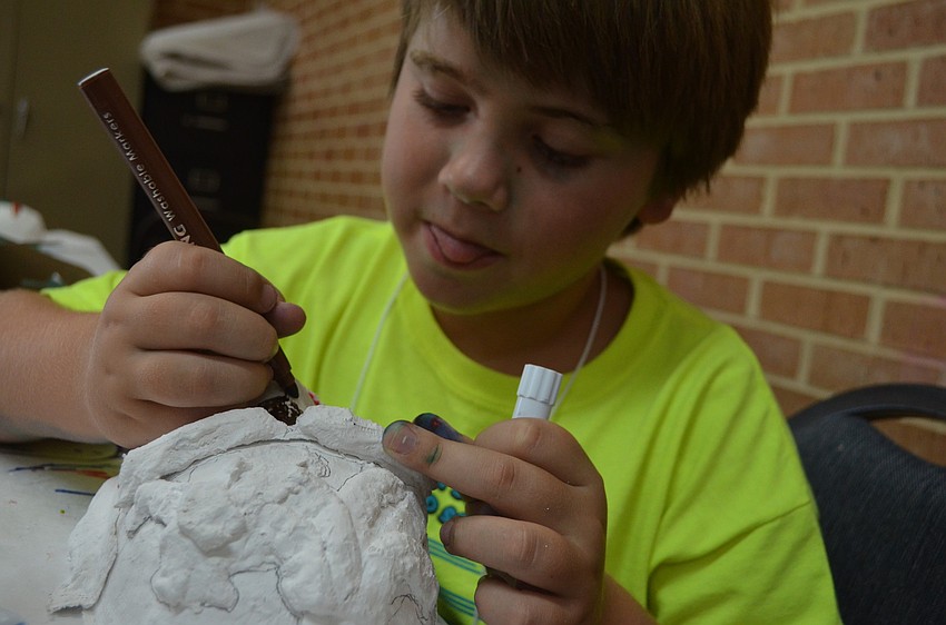 Andras Karpathy, 7, colors mask made out of plaster. The project was inspired by renaissance artist Arcimboldo.