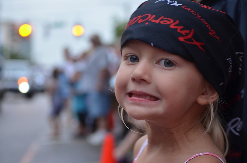 Alana Biller, 4, watches the boats pass by and collects beads.