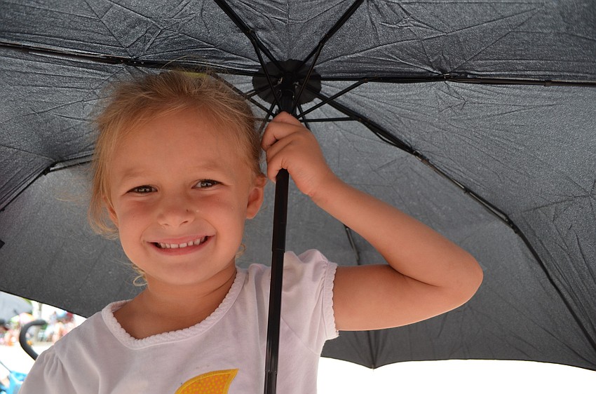 Madelyn Marsters, 4, hides under an umbrella as rain pours down on the parade.