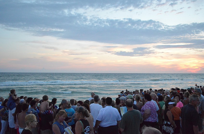 More than 400 spectators gather at the shore to watch as the baby sea turtles are led to the ocean.