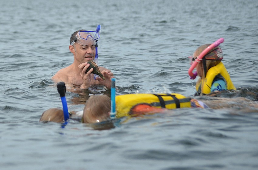 Cory Vandenhoek shows his family the conch he found in the sea grass.