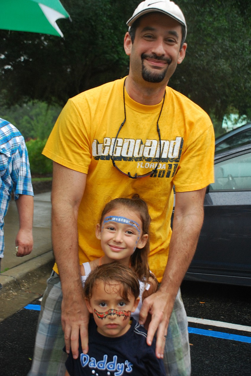 Lily and Luca Schlosberg with their dad, Joey, wait for ice cream in the rain.