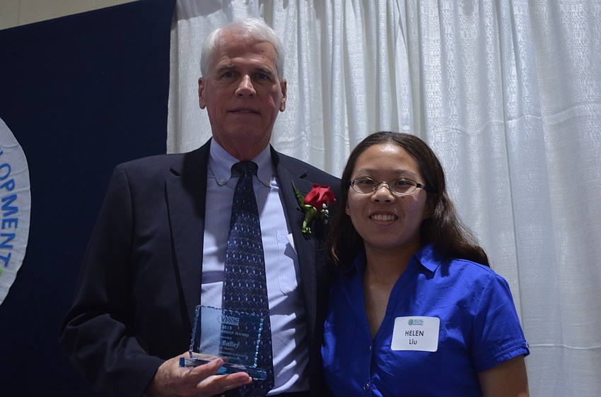 Suncoast Polytechnical High School junior Helen Liu presents honoree Dan Bailey with a trophy for his support for the organization.