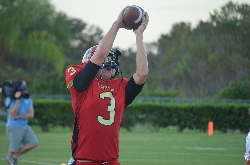 Austin Leach practices catching and throwing the football on the sidelines.