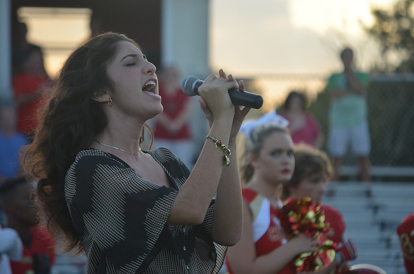Monica Gonzalez, 17, sings the National Anthem at the start of the game.