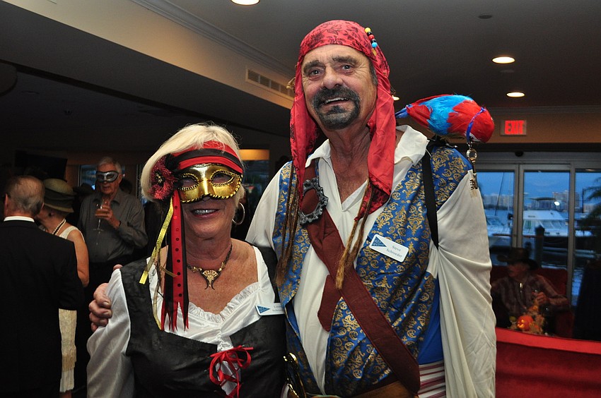 Linda and Steve Schroeder stand with party mascot â€” a bird with a key necklace.