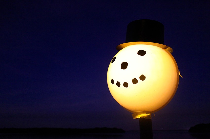A light along the pathway is decorated as a snowman.