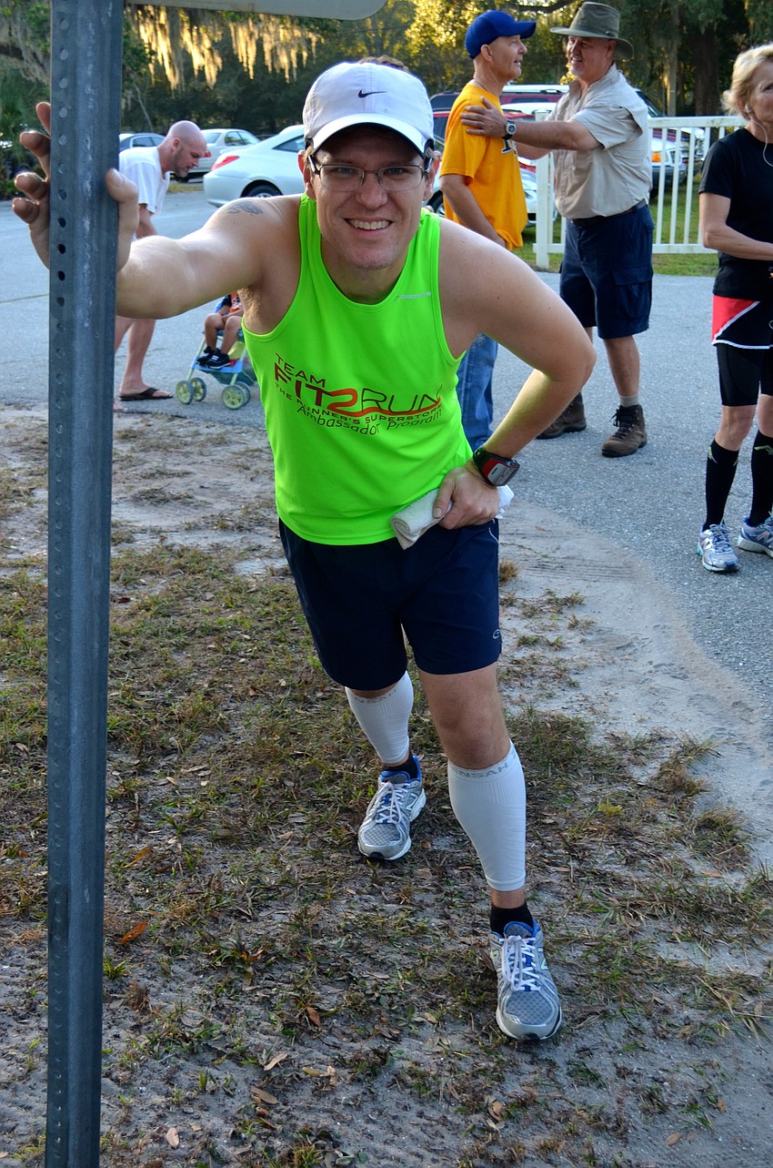 Jeff Ellis uses street signs to aid in his stretching.